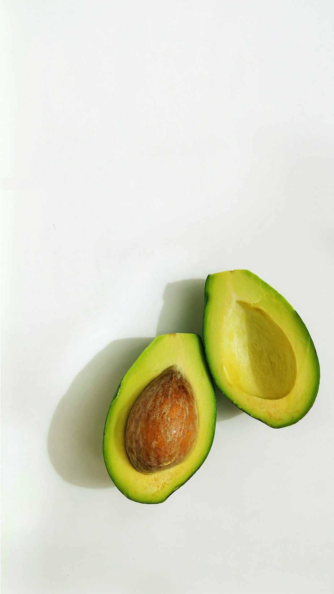 Two halves of one avocado on a white background
