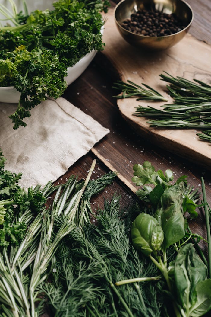 A variety of fresh herbs including rosemary, dill, and basil arranged on a wooden board for culinary use.